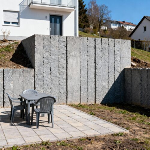 Die Rückbaupflicht droht: Eine illegale Geländeaufschüttung mit Stützmauer verletzt die Abstandsflächen zum Nachbargrundstück.